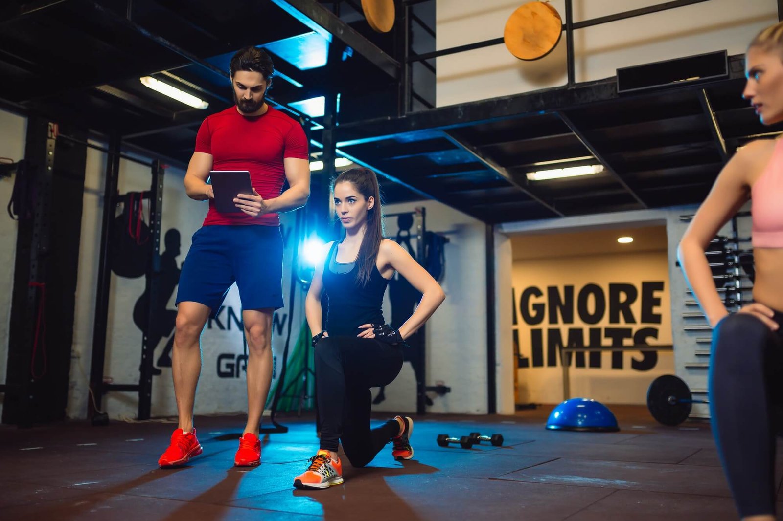 gym-instructor-assisting-two-sporty-women-with-squats-in-fitness-center-1-1.jpg